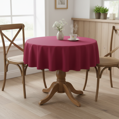 Raspberry Square tablecloth on a small kitchen table with turned wooden legs in a bright cosy UK home setting with flowers and tea