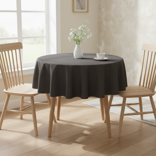 Dark grey Square tablecloth on a small kitchen table with turned wooden legs in a bright cosy UK home setting with flowers and tea